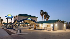 A Days Inn by Wyndham hotel with a covered entrance, palm trees, and a clear sky. - Days Inn by Wyndham Safford, AZ (Safford)
