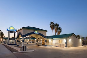 A Days Inn by Wyndham hotel with a covered entrance, palm trees, and a clear sky.