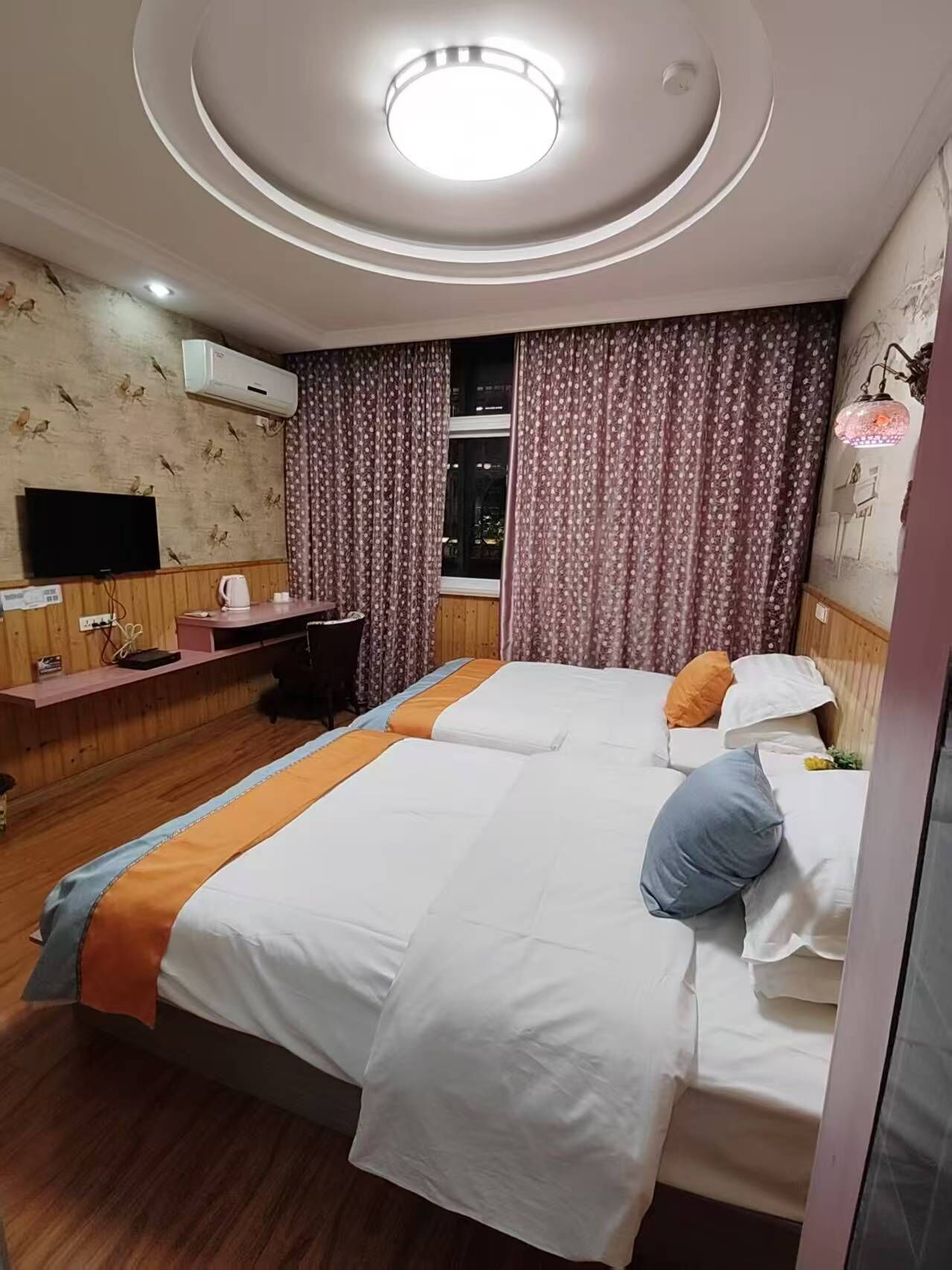 Ein Hotelzimmer mit einem Bett, einem Schreibtisch, einem Fernseher und einem fenster mit Vorhängen.