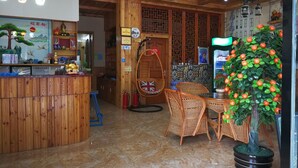 A wooden interior with a reception desk, wicker furniture, and a potted tree. - Wuzhen Youyou Inn (Jiaxing)