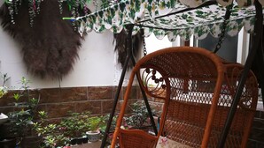 A wicker swing chair with a floral cushion, surrounded by potted plants and a decorative cloth. - Wuzhen Youyou Inn (Jiaxing)