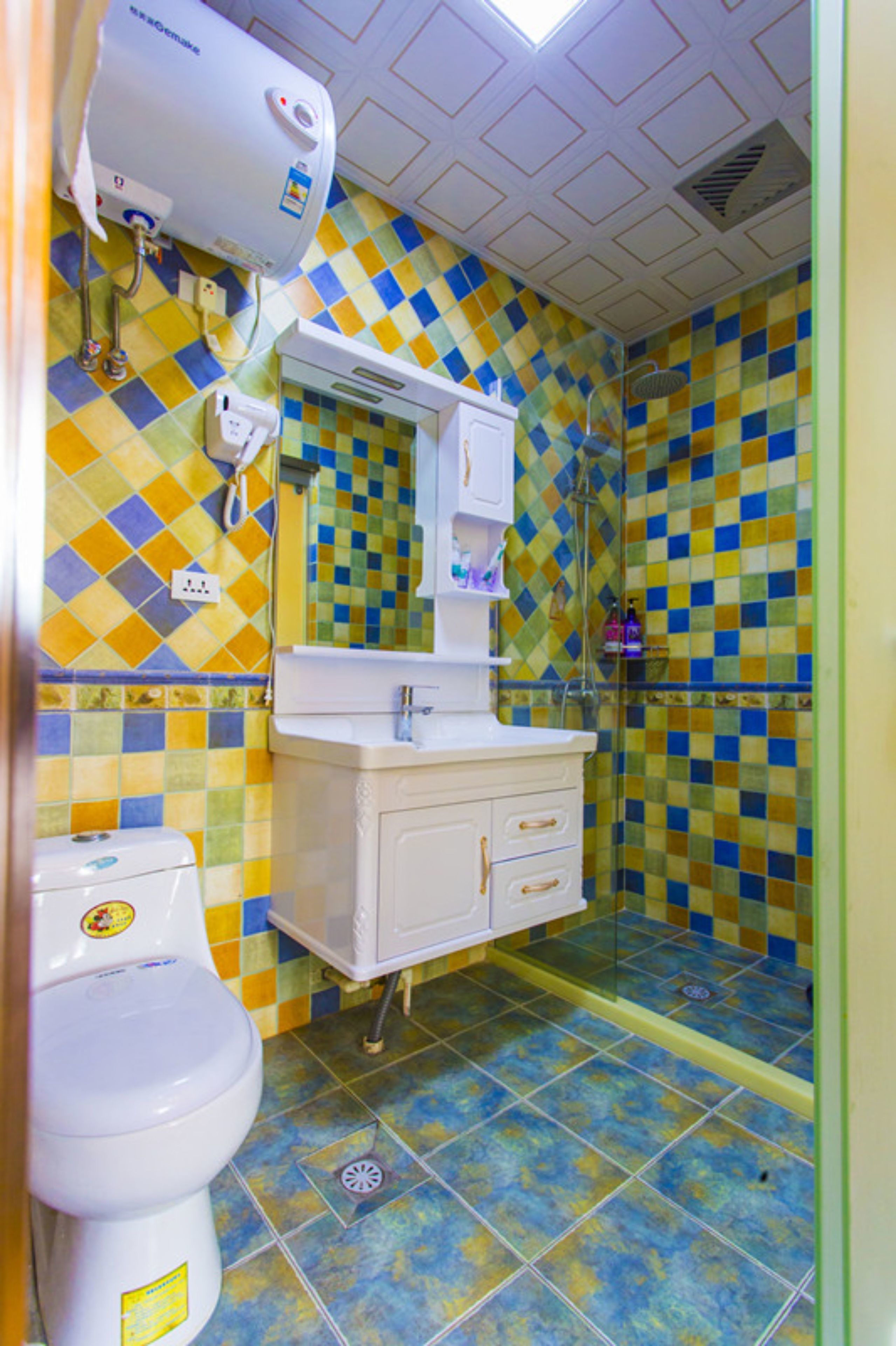 A bathroom with a toilet, sink, and shower. The walls are tiled with a checkered pattern.