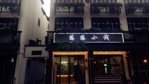 A traditional building with a signboard, multiple windows, and balconies with plants. - Wuzhen Youyou Inn (Jiaxing)