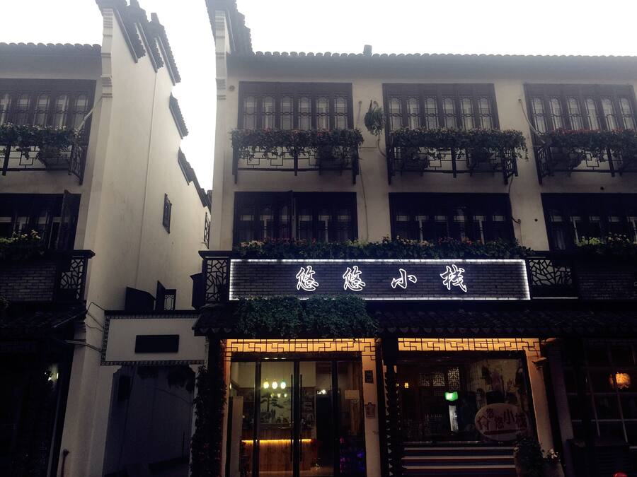 A traditional building with a signboard, multiple windows, and balconies with plants.