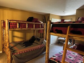 A bunk bed room with a wooden ladder, a small table, and a door in the background. - Beautiful Stratton Mountain Condo (Stratton Mountain)