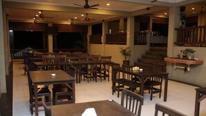 A spacious restaurant with multiple wooden tables and chairs, ceiling fans, and a TV mounted on the wall. - Redang De' Rimba Resort (Redang Island)