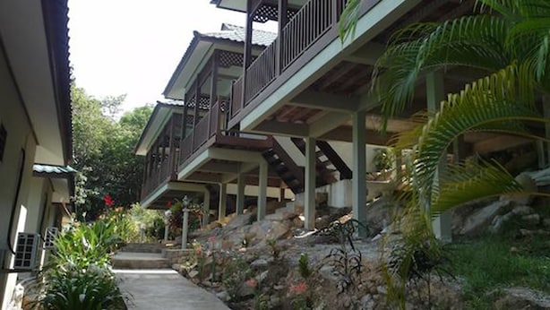 A row of two-story buildings with balconies, a concrete pathway, and tropical vegetation. - Redang De' Rimba Resort (Redang Island)