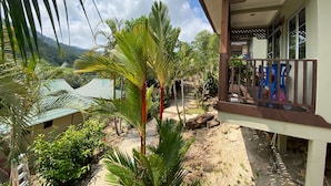 A view of a house with a porch, surrounded by lush greenery and a mountain in the background. - Redang De' Rimba Resort (Redang Island)