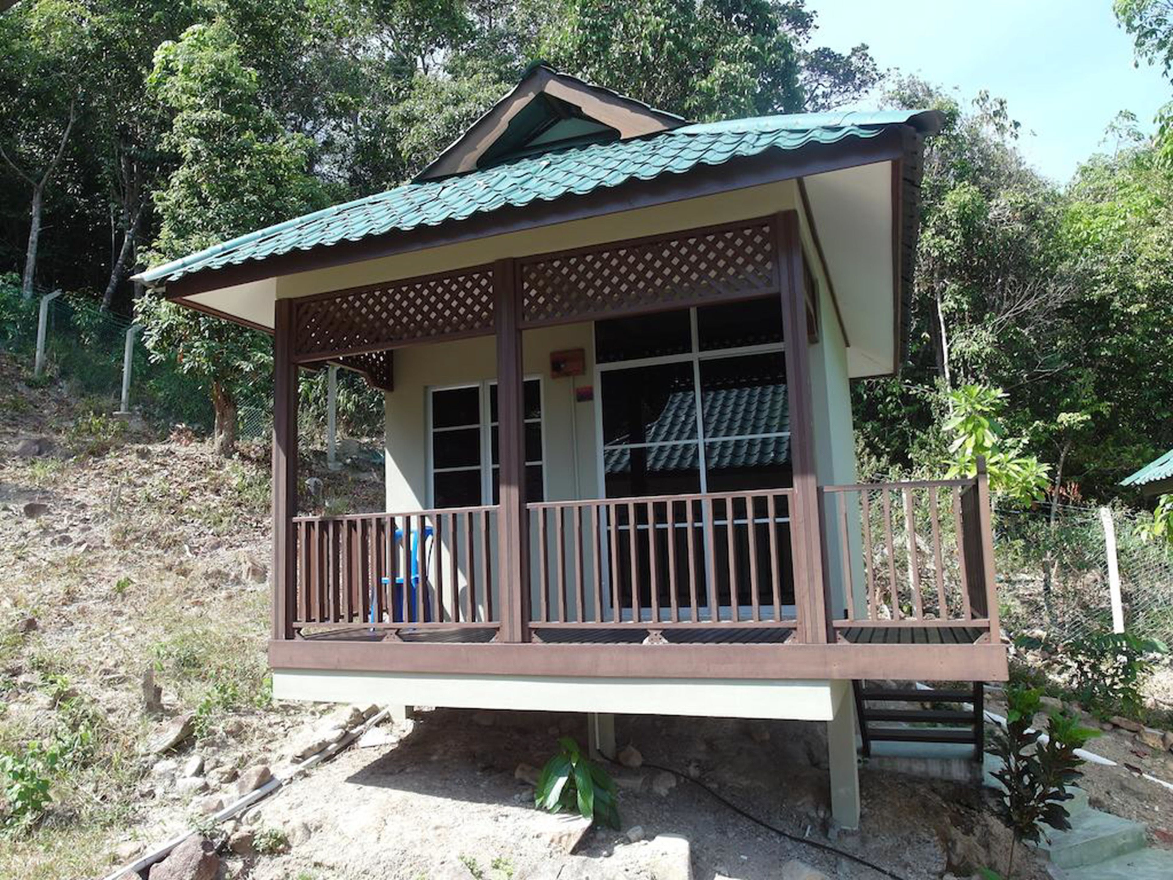 Une maison à deux étages avec un balcon, un toit en tuiles et une clôture en bois.