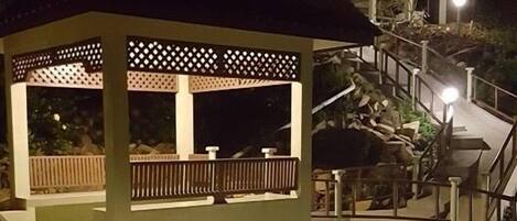 Un edificio de varios niveles con escaleras exteriores, una zona de estar cubierta y una piscina.