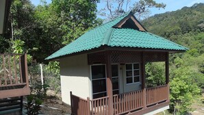 A small, elevated wooden structure with a green roof and a balcony, surrounded by natural vegetation and hills. - Redang De' Rimba Resort (Redang Island)