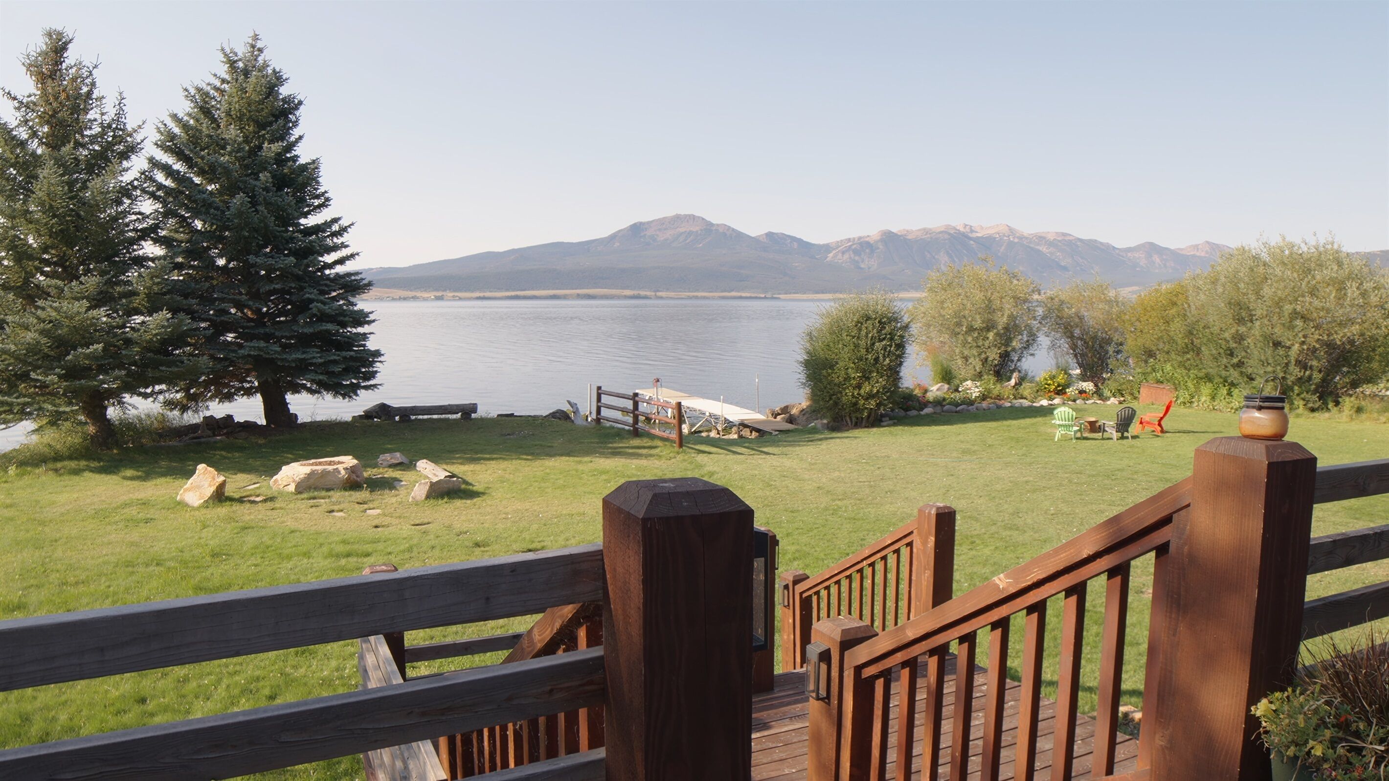 A wooden deck with a view of a lake and mountains.