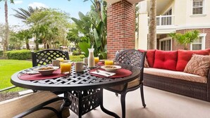 A dining area with a round table, chairs, and a red sofa. - First Floor Condo, Near Pools and Attractions (Kissimmee)