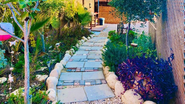 A stone pathway leading to a building with a wooden fence and lush greenery.