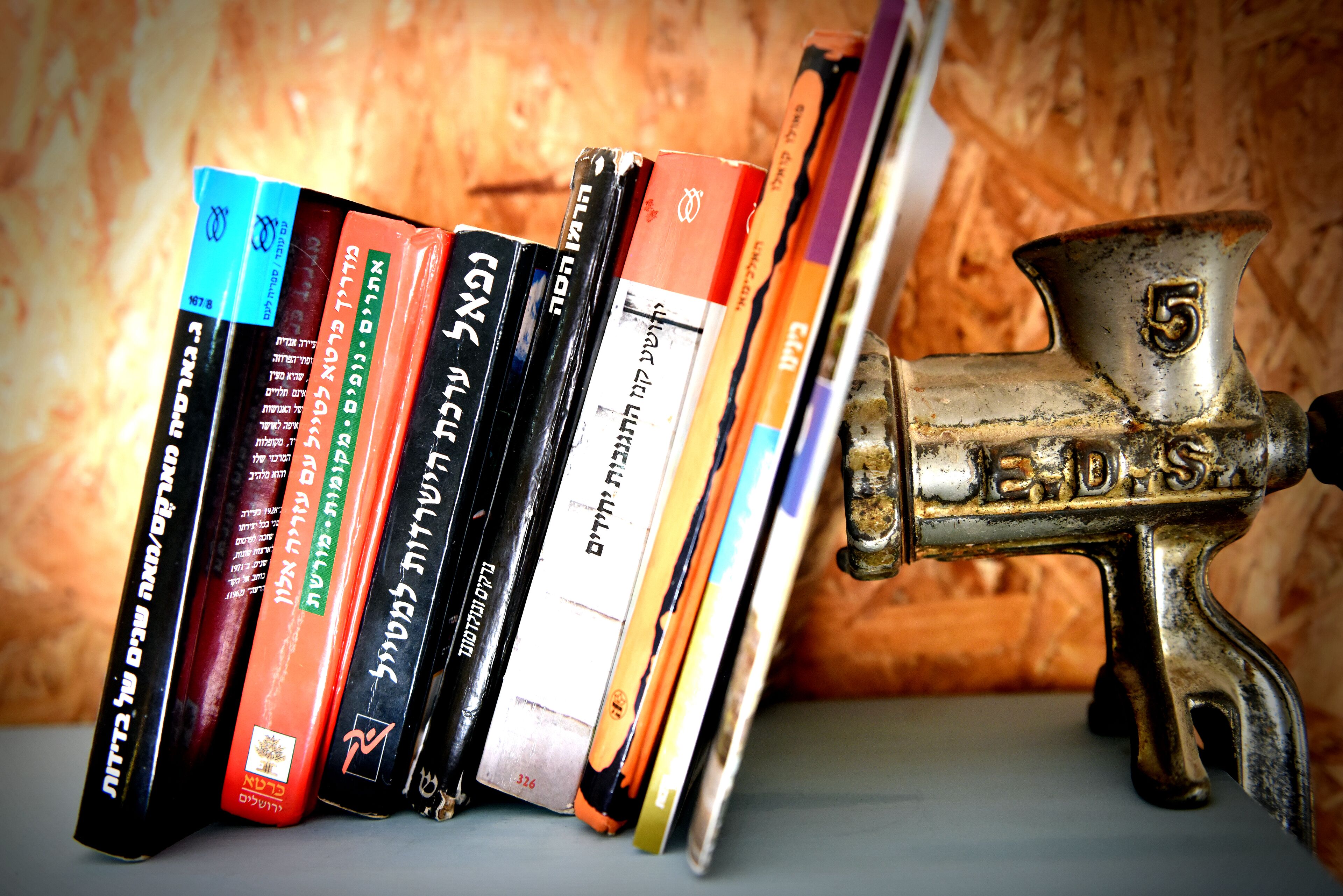 A collection of books on a shelf next to a vintage metal object.