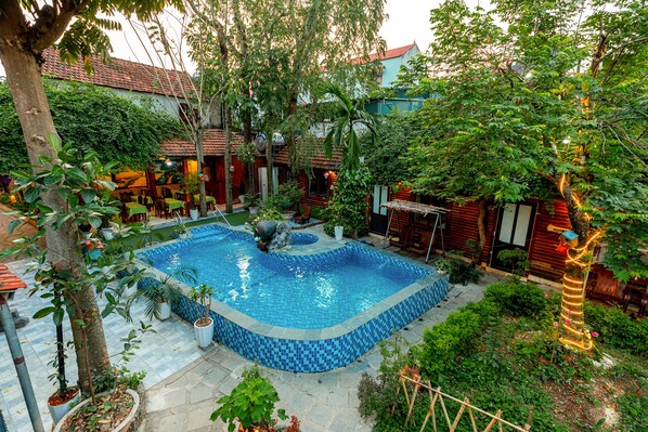 A courtyard with a swimming pool, surrounded by potted plants and trees.