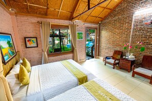 A room with two beds, a wooden ceiling, a brick wall, a window with curtains, a chair, and a small table with a vase of flowers. - Green Peace Bungalow (Nam Hoa Lu)