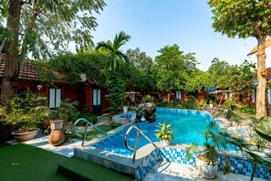 A swimming pool surrounded by lush greenery and potted plants. - Green Peace Bungalow (Nam Hoa Lu)