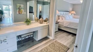 Una camera da letto moderna con un letto grande, un comodino, uno specchio e una scrivania con cassetti.