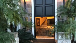 A house entrance with a dark door, stone walls, and a tiled pathway.