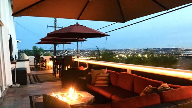 An outdoor seating area with a fire pit, red sofas, and umbrellas.