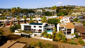 A residential area with modern houses, a swimming pool, and palm trees.