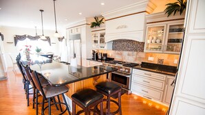 A modern kitchen with a central island, bar stools, and a dining area with a long table.