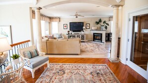 A spacious living room with a sofa, armchairs, a TV, and a fireplace.