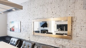 A modern conference room with a white brick wall, a large mirror, and a seating arrangement. - Modern Suite: Steps from Place des Arts (Montreal)