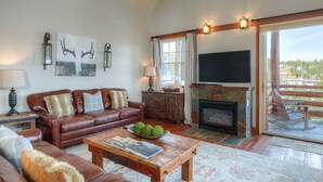 A spacious living room with a fireplace, leather sofa, and a television. - Mountain Views, Steps from the Lifts (Big Sky)