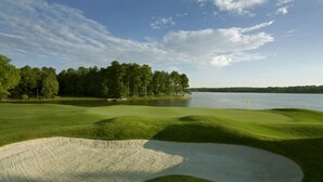 A golf course with sand bunkers, water hazards, and a forested area in the background. - Spacious Family-Friendly Retreat w/ Winter Rates! (Greensboro)