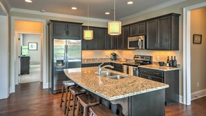 A modern kitchen with granite countertops, stainless steel appliances, and pendant lighting. - Spacious Family-Friendly Retreat w/ Winter Rates! (Greensboro)