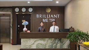 Una recepción con relojes, un letrero que dice "BRILLIANT METRI" y una planta en maceta.