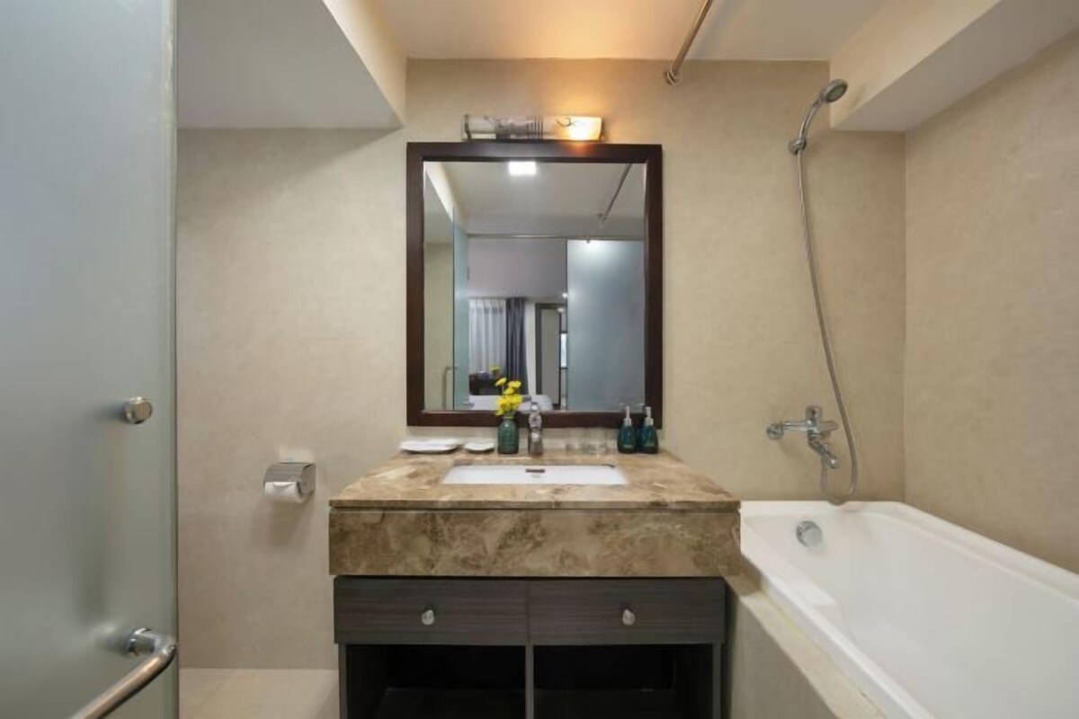 A modern bathroom with a marble sink, a large mirror, a bathtub, and a shower.