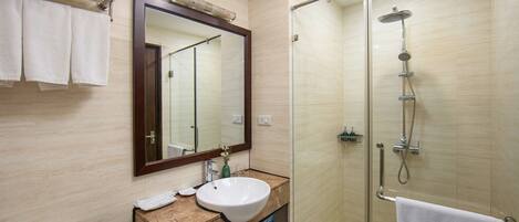 A modern bathroom with a glass-enclosed shower, a sink with a marble countertop, and a large mirror above the sink.