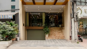 Un edificio moderno con una entrada de dos pisos, una escalera que lleva a la planta baja y un balcón con plantas.