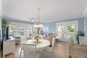 A spacious room with a dining area, a sofa set, and a television.