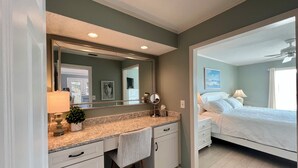 A bedroom with a bed, nightstands, a dresser, a mirror, and a ceiling fan. - Canal-Front 1BR | Quiet Retreat with Sunset Views (Destin)