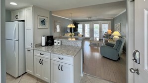 A modern kitchen with white cabinets, a refrigerator, and a coffee maker. - Canal-Front 1BR | Quiet Retreat with Sunset Views (Destin)