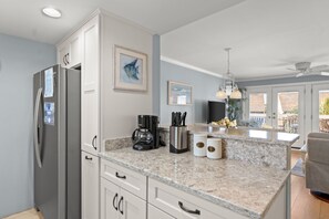 A modern kitchen with a built-in refrigerator, a coffee maker, and tea containers on the counter.