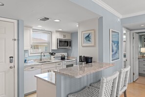 A modern kitchen with white cabinetry, a granite countertop, and a built-in microwave. - Canal-Front 1BR | Quiet Retreat with Sunset Views (Destin)