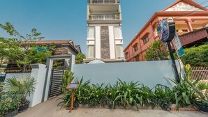 A multi-story building with a gated entrance, surrounded by lush greenery and a clear blue sky. - Villa Bayon Guides (Siem Reap)