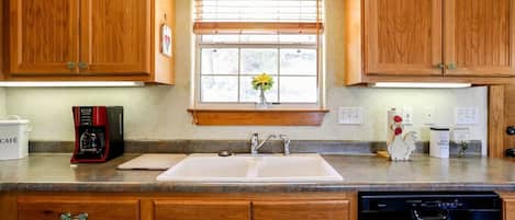 Una cocina con armarios de madera, cafetera, lavabo y lavavajillas.