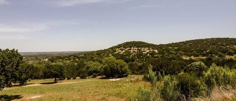A natural landscape with a hill, trees, and a clear sky.