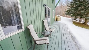 Un portico in legno verde con due poltrone in vimini e un tavolino.