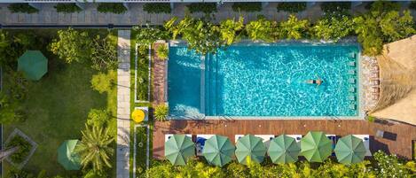 Una piscina al aire libre, sombrillas, sillones reclinables de piscina