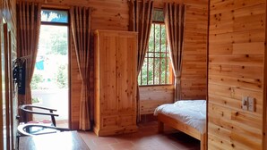 Una habitación de madera con una cama, una silla y una ventana.