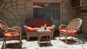 A stone wall, wicker furniture, and a window with a curtain. - Sam Houston's Retreat | Walking distance to Festivals | Close to Main Street (Fredricksburg)