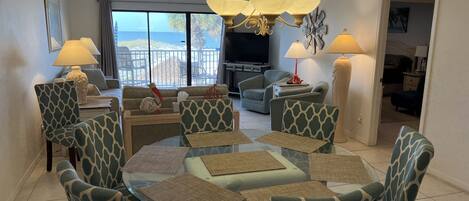 A modern living room with a round glass table, matching chairs, and a ceiling fan.