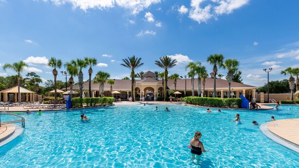 A large outdoor swimming pool with multiple lanes, surrounded by palm trees and lounge chairs. - One in a Minion themed condo, 5 mins to Disney | WiFi + Keurig (Kissimmee)